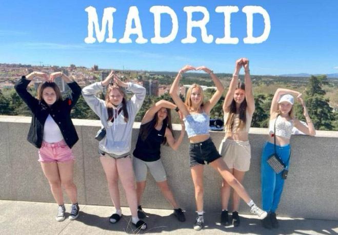 pupils on a school trip to Madrid, posing and holding up their hands to spell out MADRID